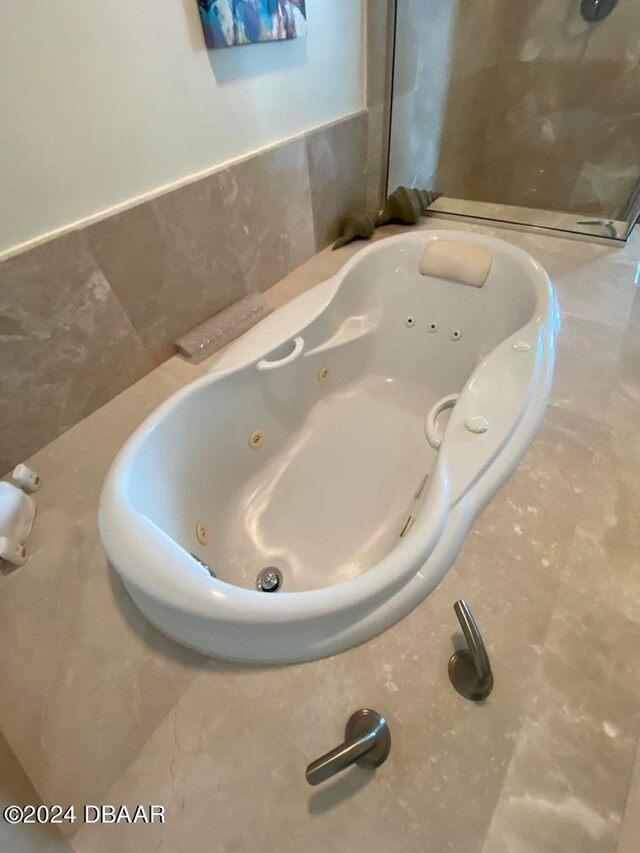 bathroom with a washtub and tile walls