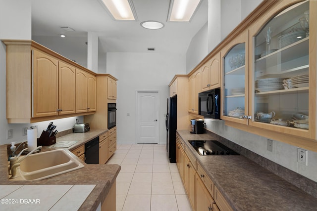 kitchen featuring sink, black appliances, light brown cabinets, light tile patterned floors, and lofted ceiling