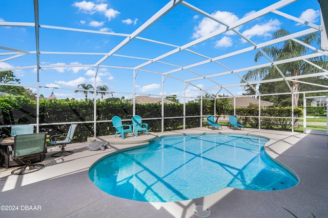 view of pool with glass enclosure and a patio