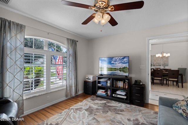 living room with hardwood / wood-style flooring and ceiling fan with notable chandelier