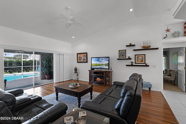 living room featuring high vaulted ceiling, ceiling fan, light hardwood / wood-style floors, and a fireplace