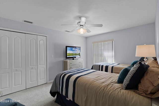 carpeted bedroom with ceiling fan and a closet