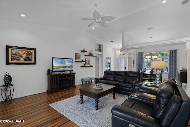 living room with ceiling fan with notable chandelier, dark hardwood / wood-style floors, and vaulted ceiling