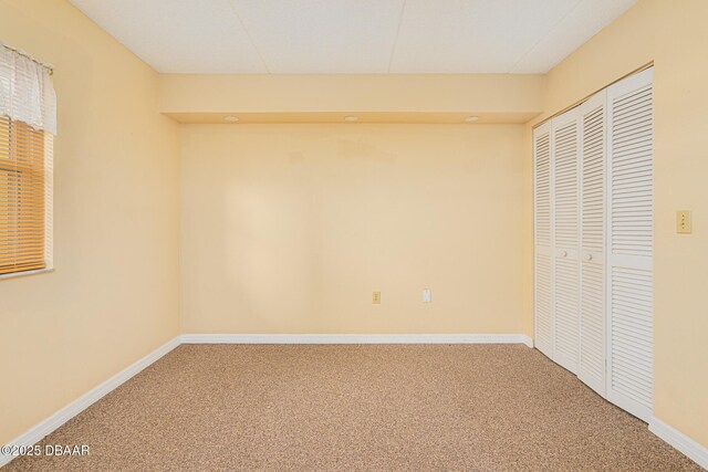 unfurnished bedroom with carpet, a closet, and baseboards