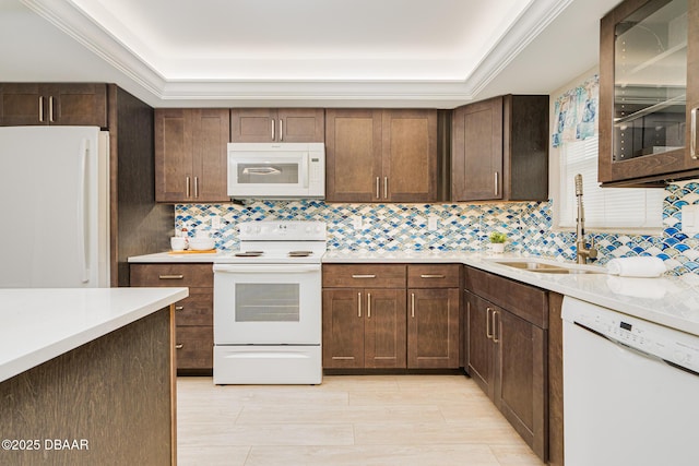 kitchen with white appliances, a sink, decorative backsplash, light countertops, and a tray ceiling