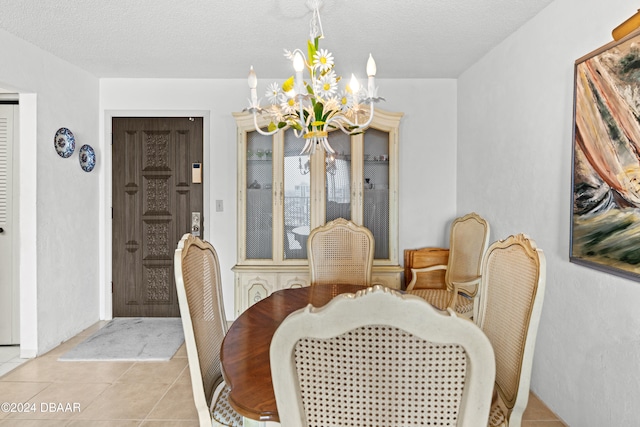 tiled dining area featuring a chandelier and a textured ceiling