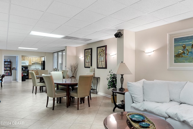 dining area with a paneled ceiling and light tile patterned floors