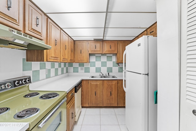 kitchen with a paneled ceiling, sink, tasteful backsplash, light tile patterned floors, and white appliances