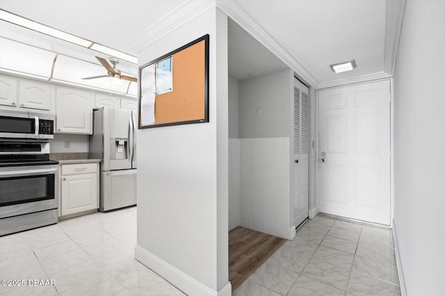 kitchen featuring ceiling fan, white cabinets, appliances with stainless steel finishes, and ornamental molding