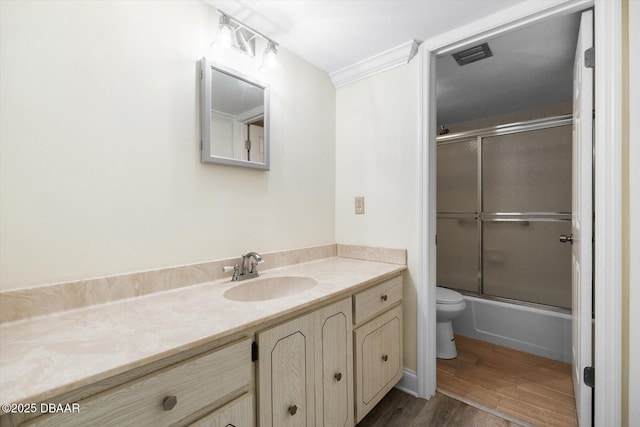 full bathroom with wood-type flooring, shower / bath combination with glass door, vanity, and toilet