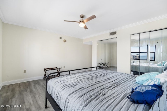 bedroom with ceiling fan, two closets, hardwood / wood-style floors, and ornamental molding