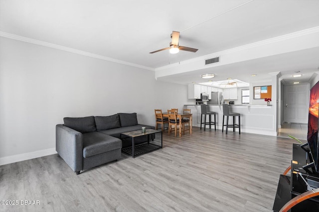 living room featuring ceiling fan, crown molding, and light hardwood / wood-style flooring