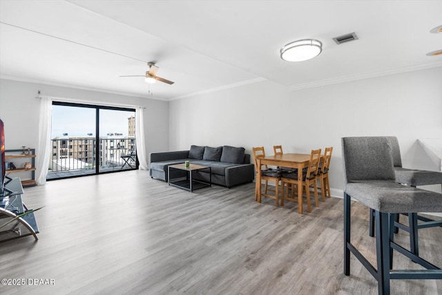 living room featuring ceiling fan, ornamental molding, and light hardwood / wood-style flooring