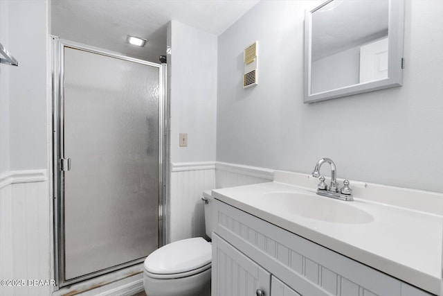 bathroom featuring a shower with shower door, toilet, and vanity