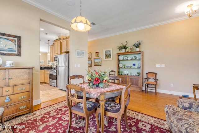 dining space with light hardwood / wood-style flooring and ornamental molding