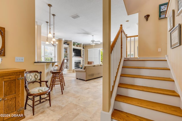 stairs with a textured ceiling and ceiling fan with notable chandelier