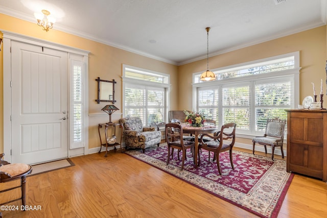 dining space with ornamental molding and light hardwood / wood-style flooring