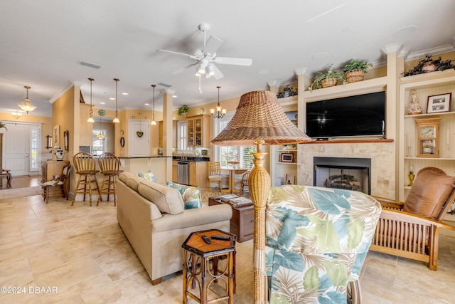 living room with a tiled fireplace, ceiling fan with notable chandelier, and ornamental molding