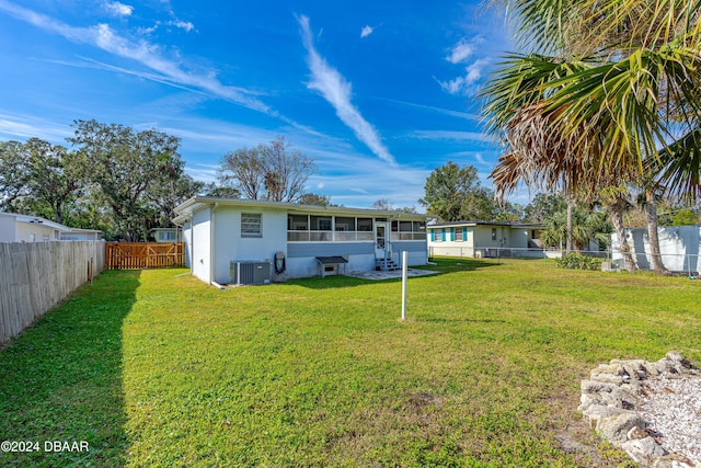 rear view of property with a yard and central air condition unit