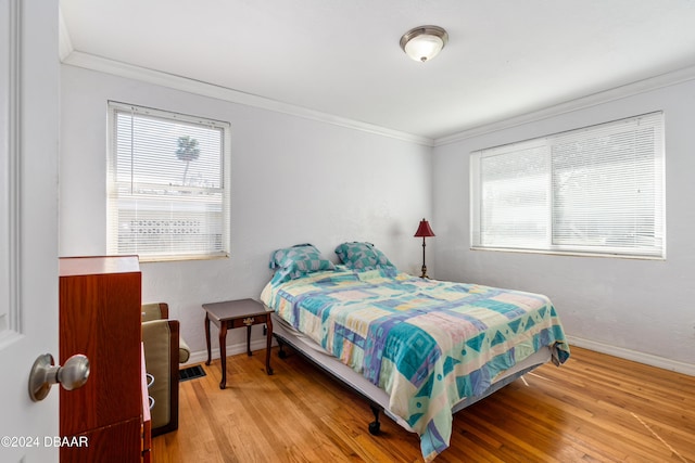 bedroom featuring multiple windows, crown molding, and light hardwood / wood-style floors