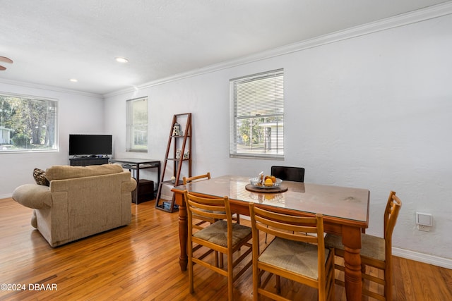 dining area with light hardwood / wood-style floors, a healthy amount of sunlight, and crown molding