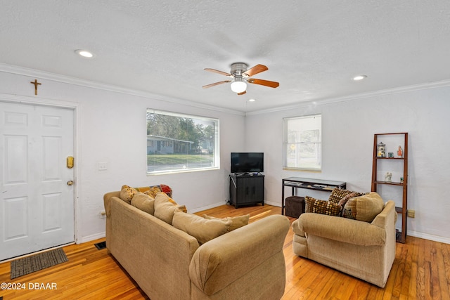 living room with a textured ceiling, light hardwood / wood-style flooring, ceiling fan, and ornamental molding