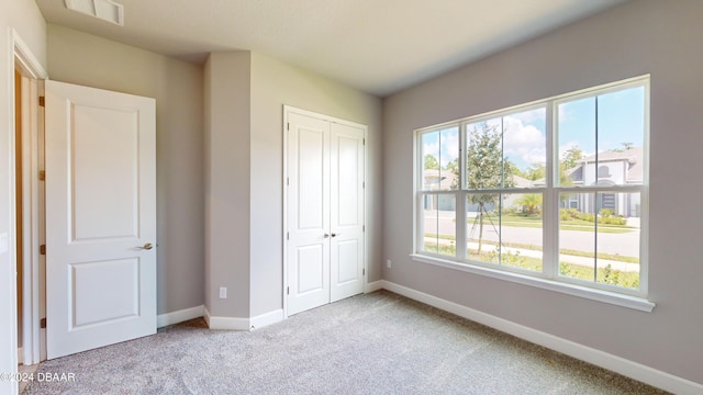 unfurnished bedroom featuring light colored carpet, multiple windows, and a closet