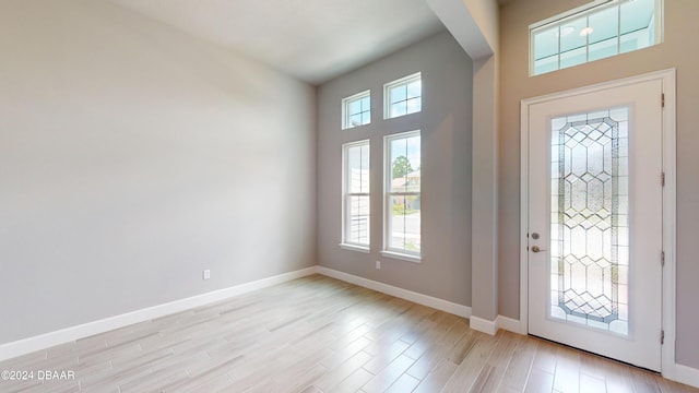 entryway with light wood-type flooring and a towering ceiling