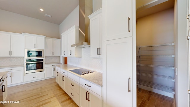 kitchen featuring wall chimney exhaust hood, white cabinetry, light hardwood / wood-style flooring, and appliances with stainless steel finishes