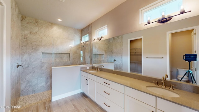 bathroom featuring toilet, vanity, hardwood / wood-style flooring, and tiled shower