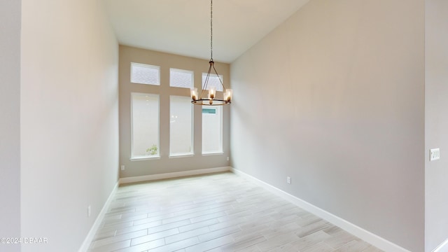 unfurnished dining area featuring a notable chandelier and light hardwood / wood-style floors