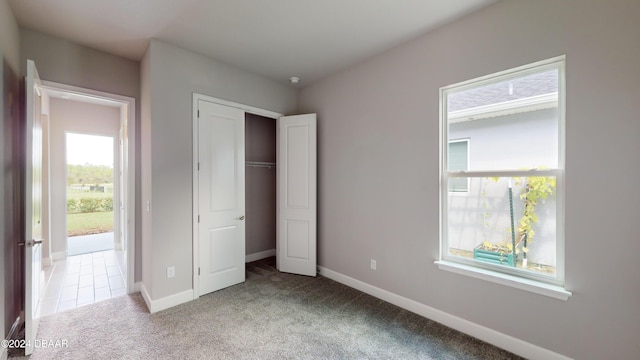 unfurnished bedroom with light carpet and a closet