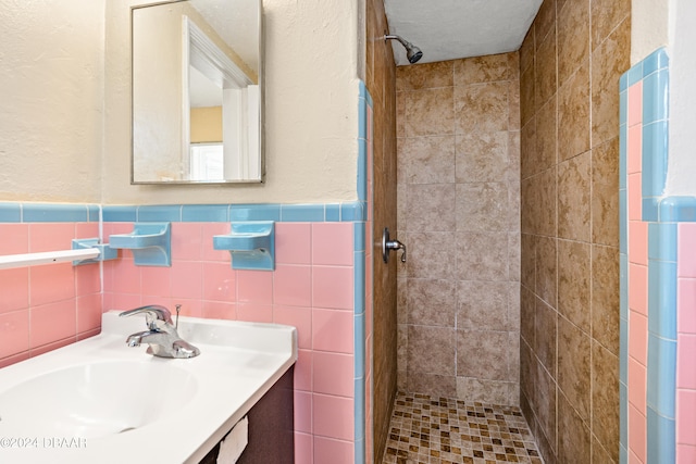 bathroom with tile walls, vanity, and a tile shower