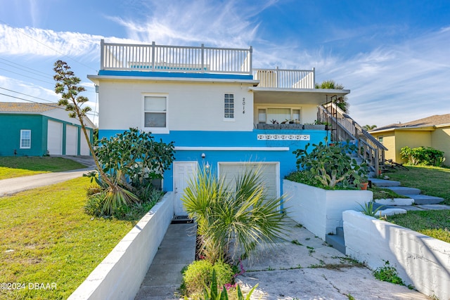 view of front of home featuring a garage, a front lawn, and a balcony