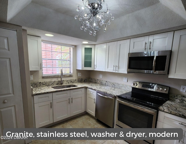 kitchen with stainless steel appliances, light stone counters, a sink, and white cabinets