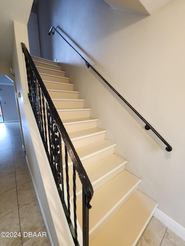 stairway featuring baseboards and tile patterned floors