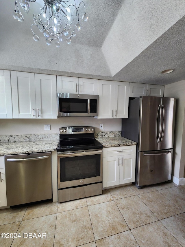 kitchen with appliances with stainless steel finishes, white cabinets, and light tile patterned floors