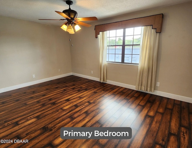 spare room featuring dark wood-style floors, a textured ceiling, and baseboards