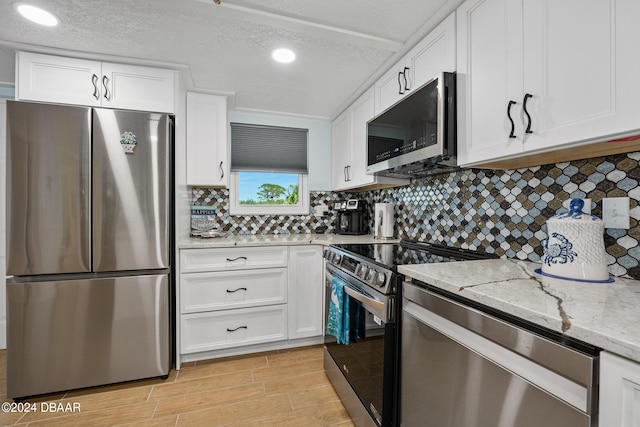 711 N Halifax Ave Unit 405, Daytona Beach, FL 32118 - kitchen with tasteful backsplash, stainless steel appliances, light wood-type flooring, white cabinetry, and light stone countertops