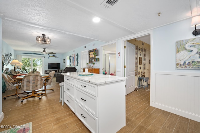711 N Halifax Ave Unit 405, Daytona Beach, FL 32118 - kitchen featuring light stone counters, a textured ceiling, light hardwood / wood-style floors, white cabinets, and ceiling fan