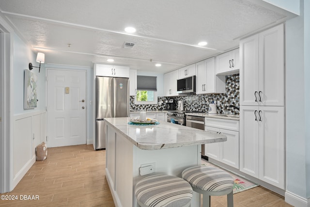 711 N Halifax Ave Unit 405, Daytona Beach, FL 32118 - kitchen with white cabinets, a kitchen breakfast bar, stainless steel appliances, and light hardwood / wood-style flooring