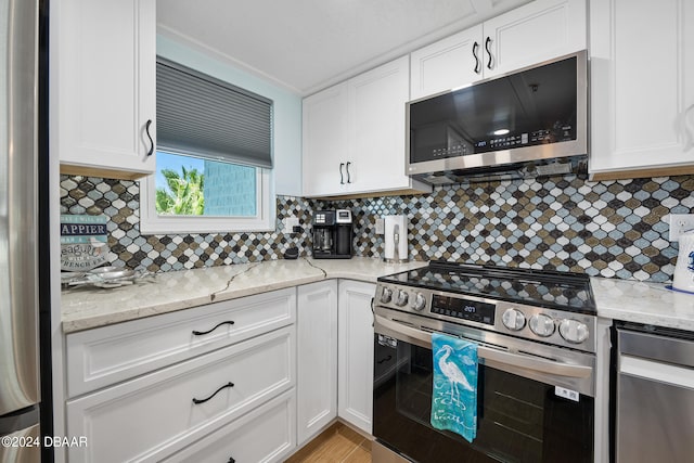 711 N Halifax Ave Unit 405, Daytona Beach, FL 32118 - kitchen featuring white cabinets, decorative backsplash, stainless steel appliances, and light stone counters