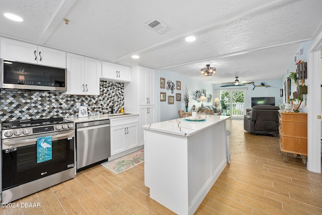 711 N Halifax Ave Unit 405, Daytona Beach, FL 32118 - kitchen with stainless steel appliances, ceiling fan, a kitchen island, white cabinetry, and light hardwood / wood-style flooring