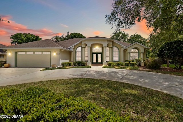 1320 Antrim Cir, Ormond Beach, FL 32174 - view of front of house with french doors, a garage, a lawn, curved driveway, and stucco siding