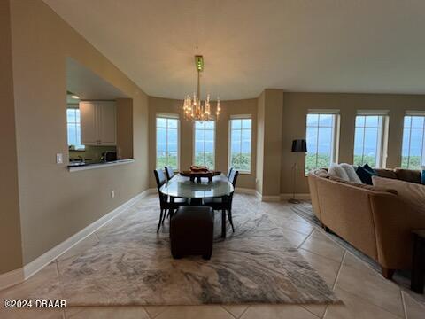 tiled dining room featuring a chandelier and plenty of natural light