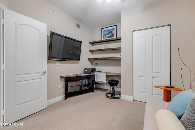 interior space featuring built in desk, a textured ceiling, light carpet, and ceiling fan