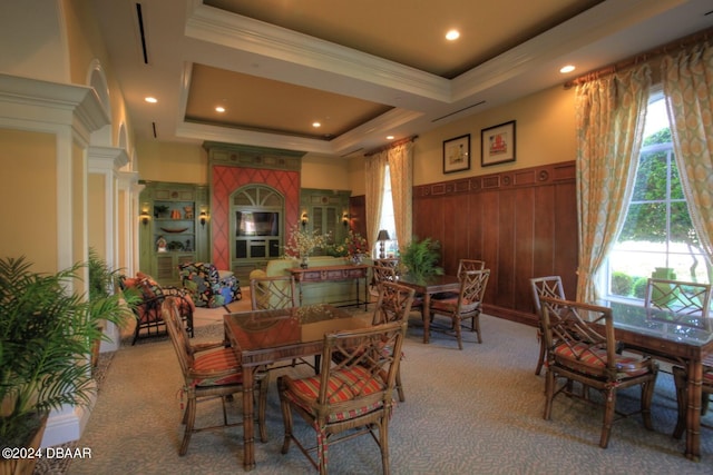 dining room featuring carpet, a wealth of natural light, wooden walls, and a raised ceiling