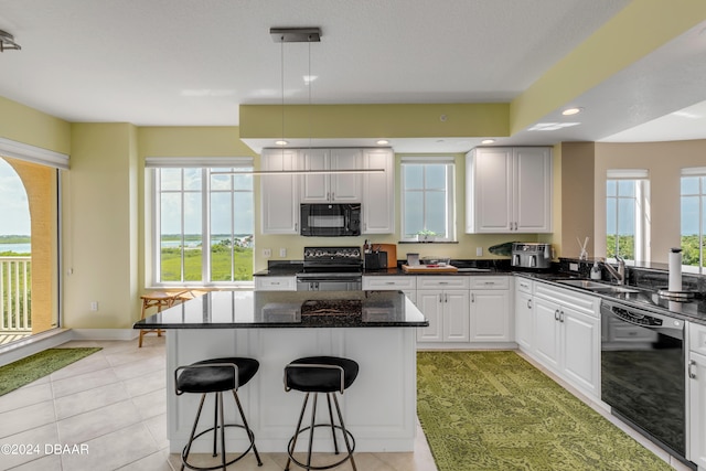 kitchen featuring pendant lighting, a center island, black appliances, light tile patterned floors, and white cabinetry