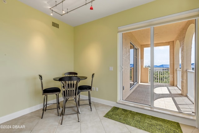 dining area featuring a mountain view, rail lighting, and light tile patterned flooring