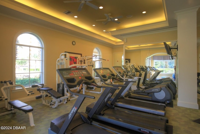 gym featuring a raised ceiling, ceiling fan, and crown molding